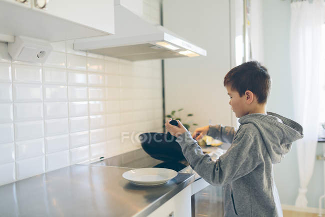Niño joven cocinando en la cocina doméstica - foto de stock
