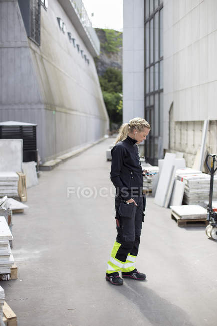 Visão lateral do trabalhador da construção com as mãos nos bolsos, foco em primeiro plano — Fotografia de Stock