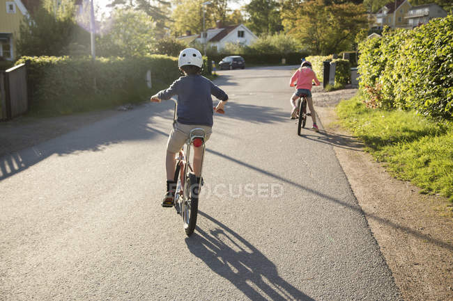 Vista trasera de los niños en bicicleta en el día soleado - foto de stock