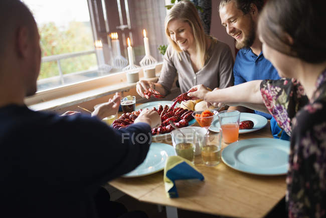 Люди, сидящие за столом во время вечеринки раков, избирательный фокус — стоковое фото