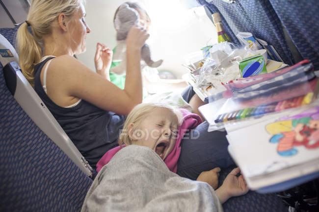 Donna con bambino sbadigliante in aereo, attenzione selettiva — Foto stock