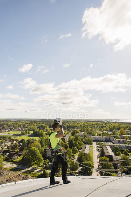 Ouvrier de la construction sur le toit contre le ciel avec des nuages — Photo de stock