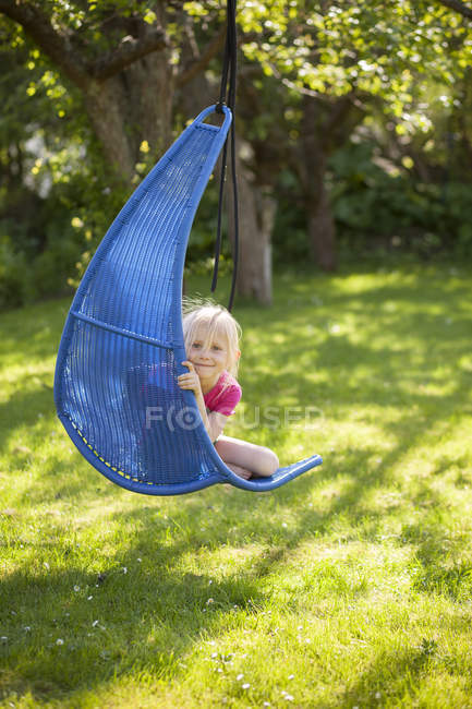 Girl sitting in hanging chair, focus on foreground — Stock Photo