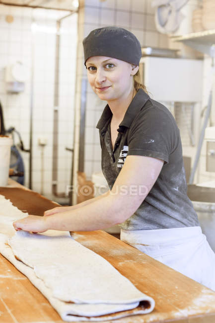 Retrato de panadero sosteniendo la masa y mirando a la cámara - foto de stock