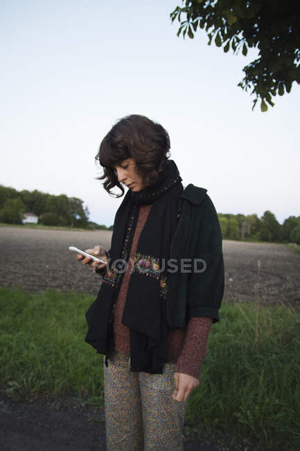 Jovem mulher usando telefone inteligente em campo — Fotografia de Stock
