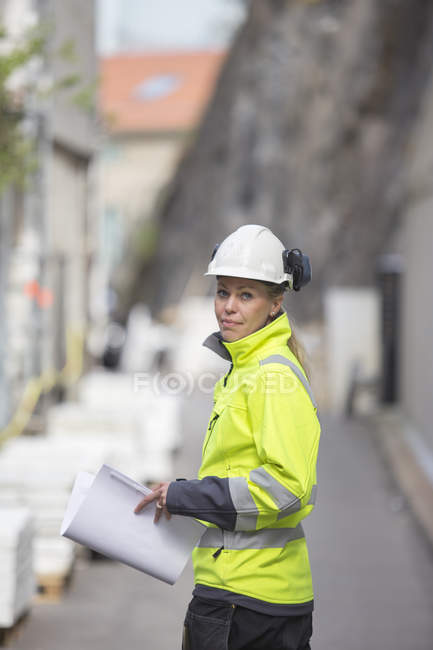 Construction worker with blueprints, focus on foreground — Stock Photo