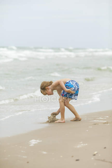 Мальчик строит песчаный замок на пляже Дании — стоковое фото