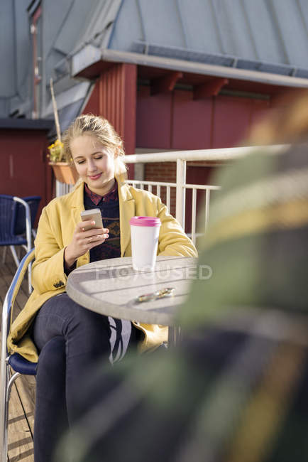 Young woman using smart phone and drinking coffee — Stock Photo