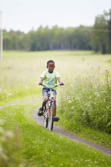 Хлопчик їде на велосипеді в полі, вибірковий фокус — стокове фото