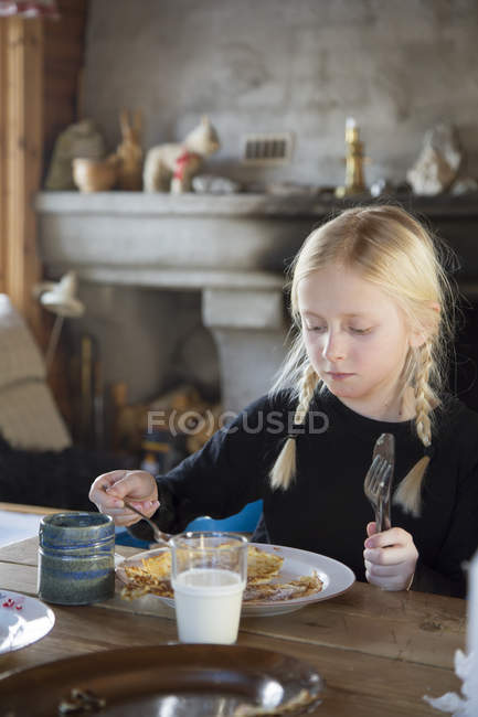 Girl eating pancakes for breakfast, focus on foreground — Stock Photo