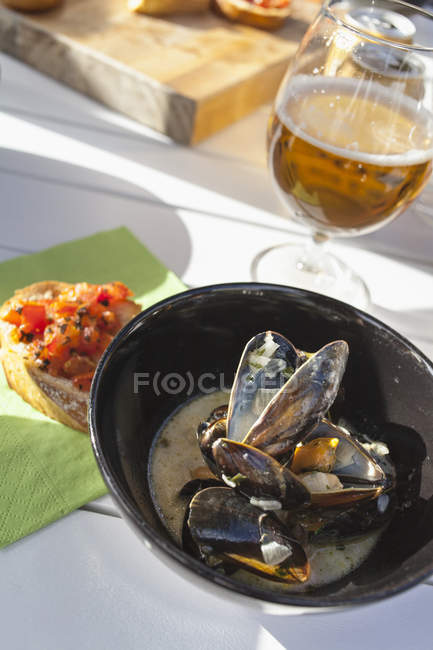 Mussel soup, bruschetta and beer glass on wooden table — Stock Photo