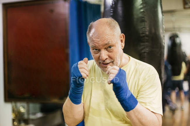 Старший мужчина с поднятыми кулаками на тренировках по боксу — стоковое фото