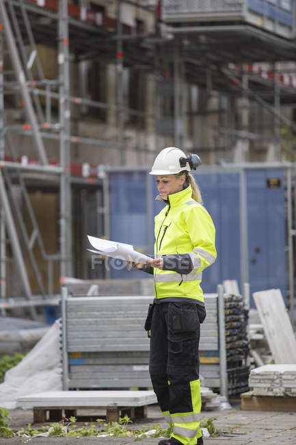 Construction worker looking at blueprints, focus on foreground — Stock Photo