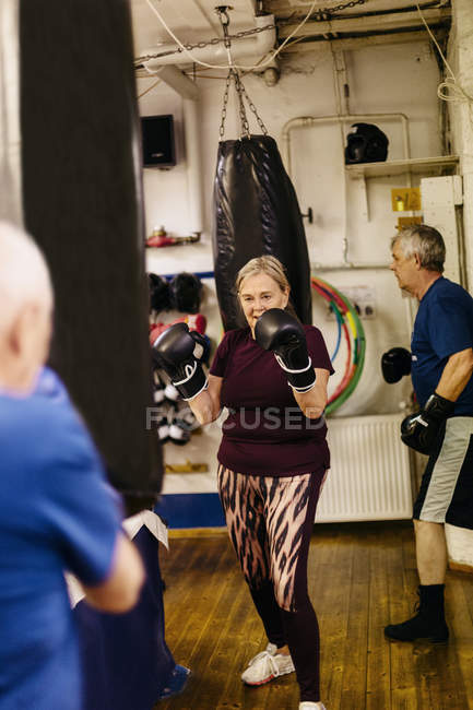 Senior woman training with punching bag, selective focus — Stock Photo