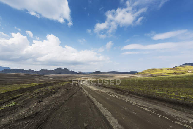 Camino de tierra bajo el cielo azul en Islandia - foto de stock