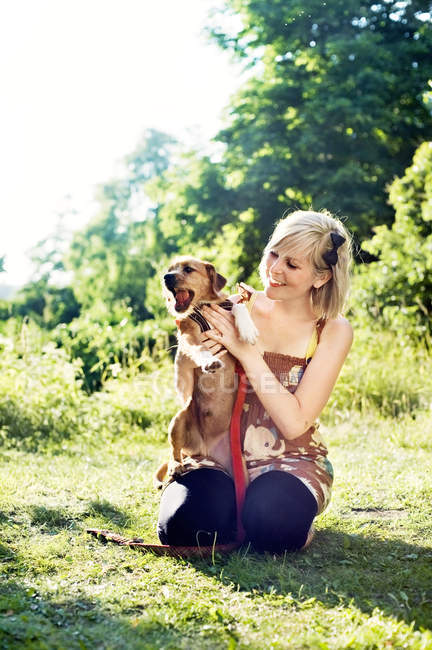 Jovem mulher sentada na grama com terrier — Fotografia de Stock