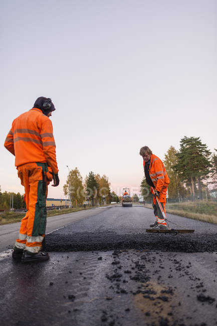 Trois ouvriers réparent la route — Photo de stock