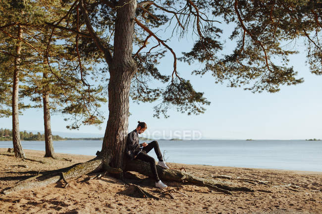 Jovem ao ar livre usando telefone inteligente na praia — Fotografia de Stock