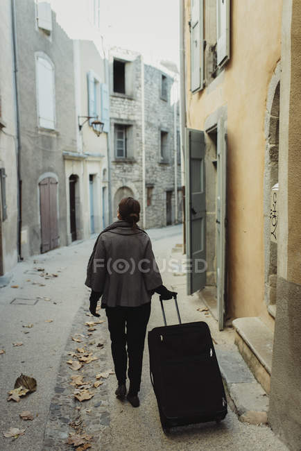 Young woman walking with luggage in old town — Stock Photo