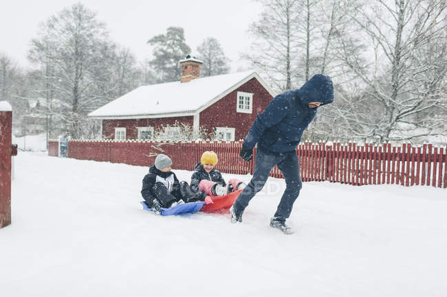 Людина тягне дітей на санях на зиму, зосередитися на передньому плані — стокове фото