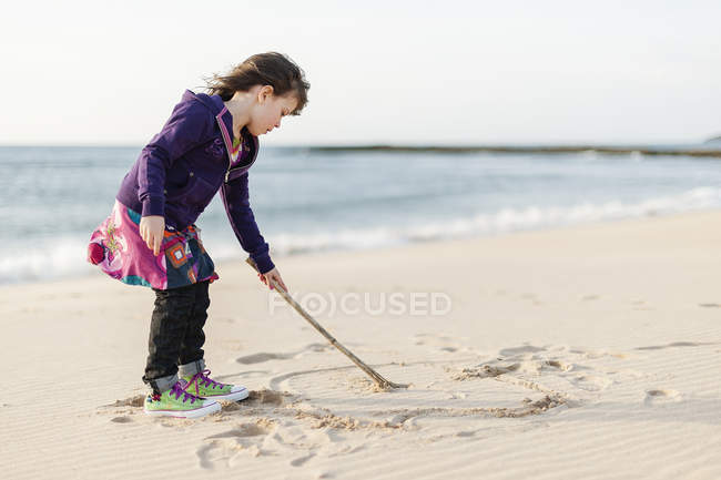 Girl drawing on beach sand in Alantejo, Portugal — Stock Photo