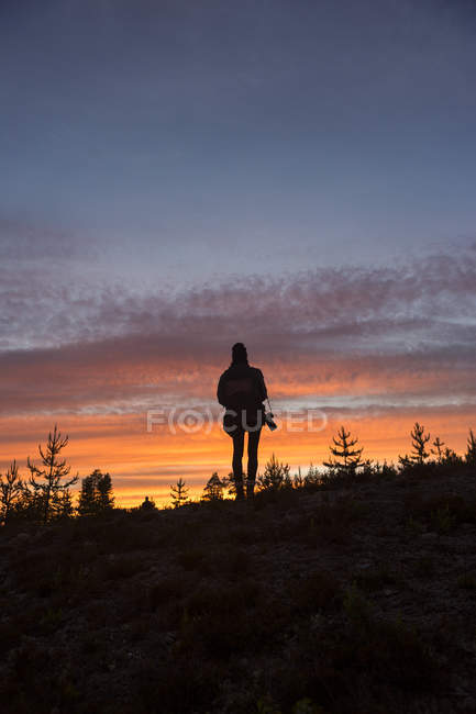 Silhueta de mulher com câmera ao pôr do sol — Fotografia de Stock