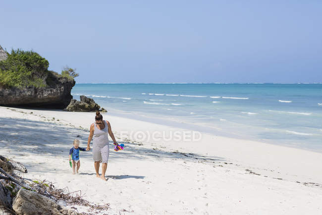 Madre e hijo caminando en Diani Beach, Kenia - foto de stock