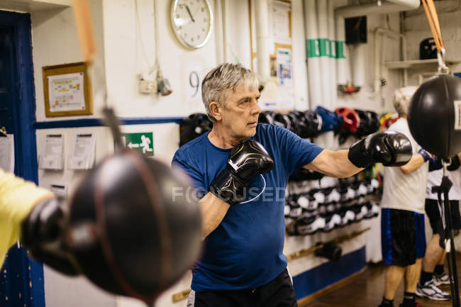 Hombres mayores entrenando con sacos de boxeo, enfoque selectivo - foto de stock