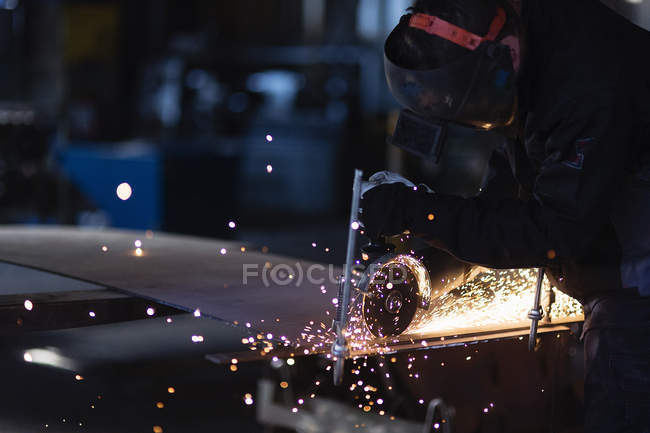 Young man cutting metal in workshop, differential focus — Stock Photo