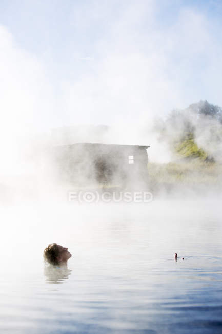 Vista lateral da mulher tomando banho em Secret Lagoon, Islândia — Fotografia de Stock