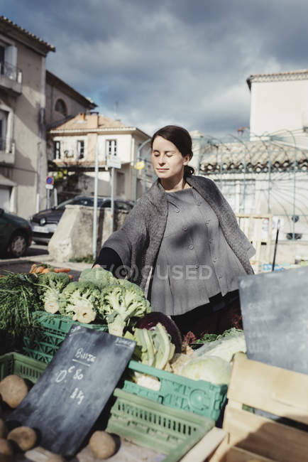 Young woman choosing vegetables on market — Stock Photo