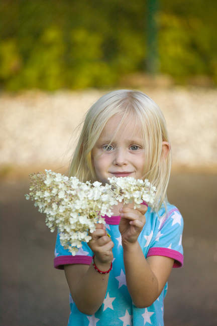 Portrait of girl holding flowers, focus on foreground — Stock Photo