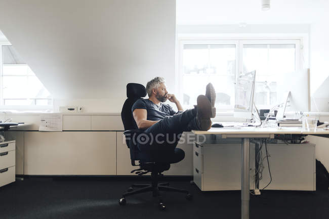 Бізнесмен використовує настільний комп'ютер і дивиться вбік — стокове фото