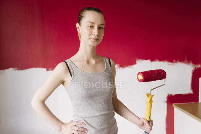 Portrait de femme avec rouleau de peinture contre mur — Photo de stock