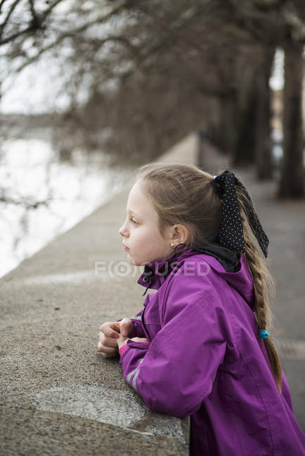 Молода дівчина спирається на бетонну стіну, фокус на передньому плані — стокове фото