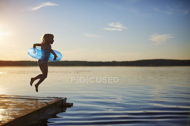 Вид збоку дівчини, що стрибає з пірсу — стокове фото