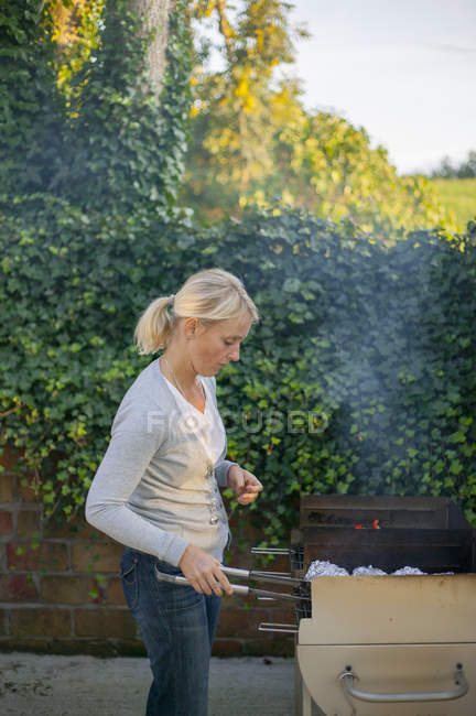 Жінка готує на задньому дворі, вибірковий фокус — стокове фото