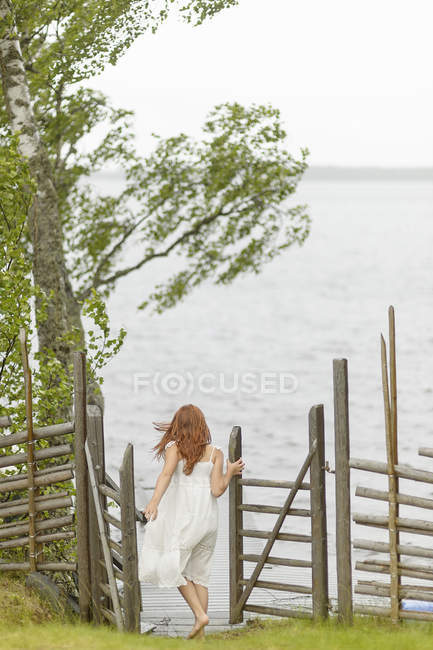 Vista trasera de la niña caminando hacia el lago, enfoque selectivo - foto de stock