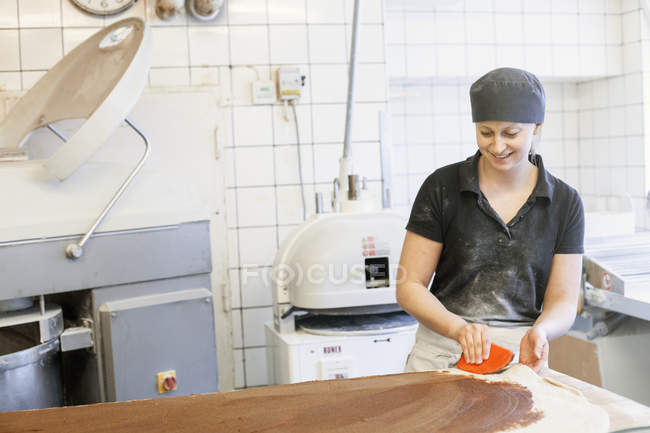 Baker espalhando farinha no balcão da cozinha — Fotografia de Stock