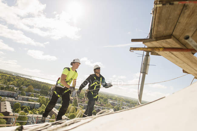 Trabajadores de la construcción en el techo, enfoque diferencial - foto de stock