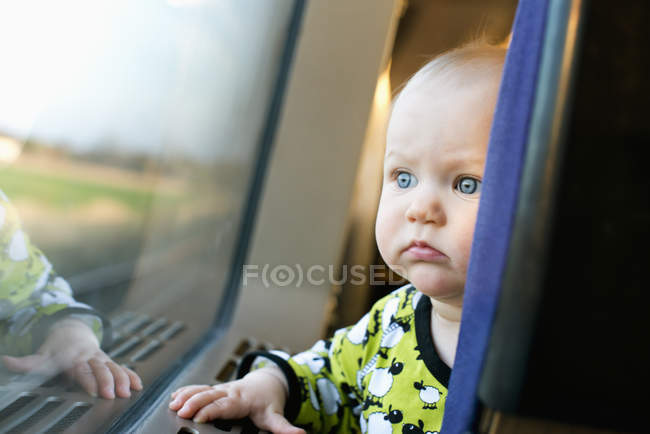 Baby girl looking out window of train — Stock Photo
