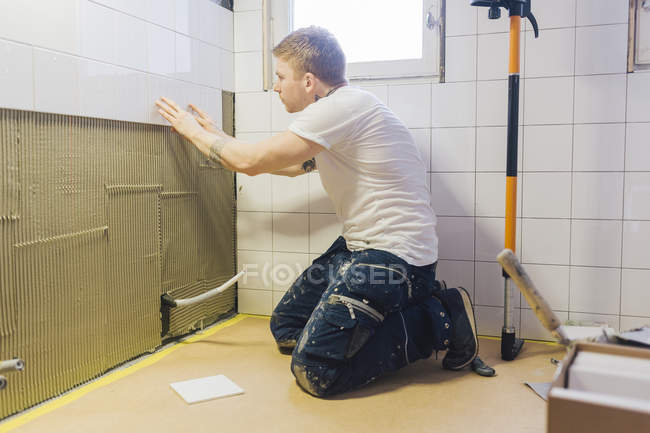 Tiler aplicando telhas na parede no banheiro — Fotografia de Stock