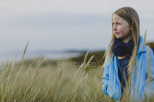 Jeune fille dans l'herbe longue, se concentrer sur le premier plan — Photo de stock