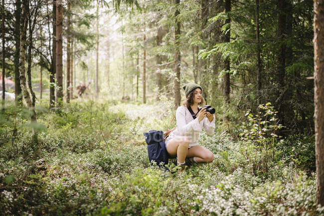 Молода жінка робить фото з камерою в лісі — стокове фото