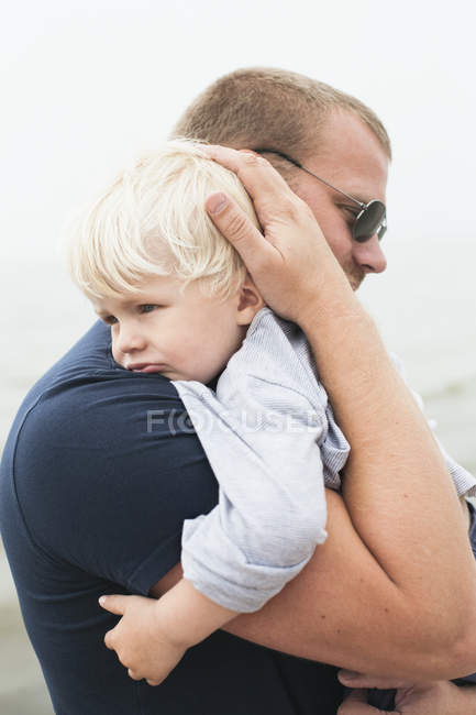 Man embracing boy, focus on foreground — Stock Photo