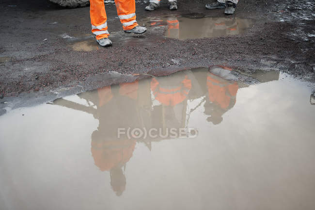Miners reflecting in puddle, selective focus — Stock Photo