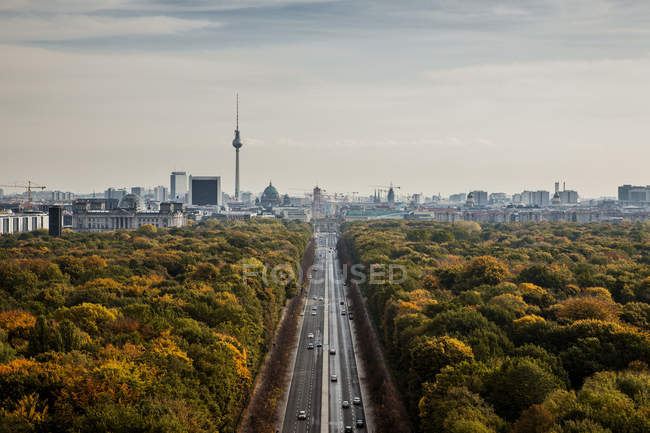 Aerial view of road traffic between woods and cityscape — Stock Photo