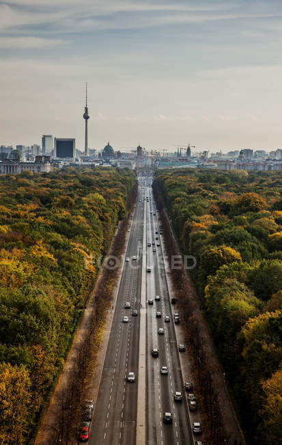 Aerial view of road traffic between woods and cityscape — Stock Photo
