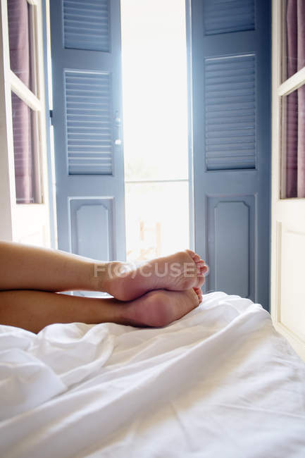 Ausgeschnittene Ansicht einer Person, die auf dem Bett im Zimmer liegt — Stockfoto