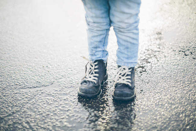Cropped view child standing on asphalt, selective focus — Stock Photo